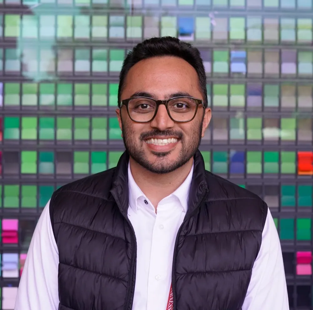 Dip Patel smiling, wearing glasses and a dark vest